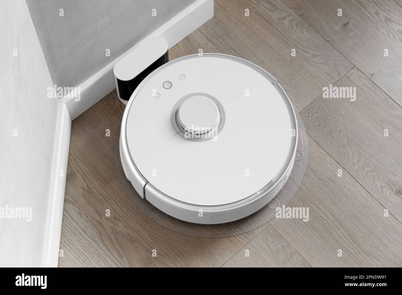 White robot vacuum cleaner is charging on the docking station, smart