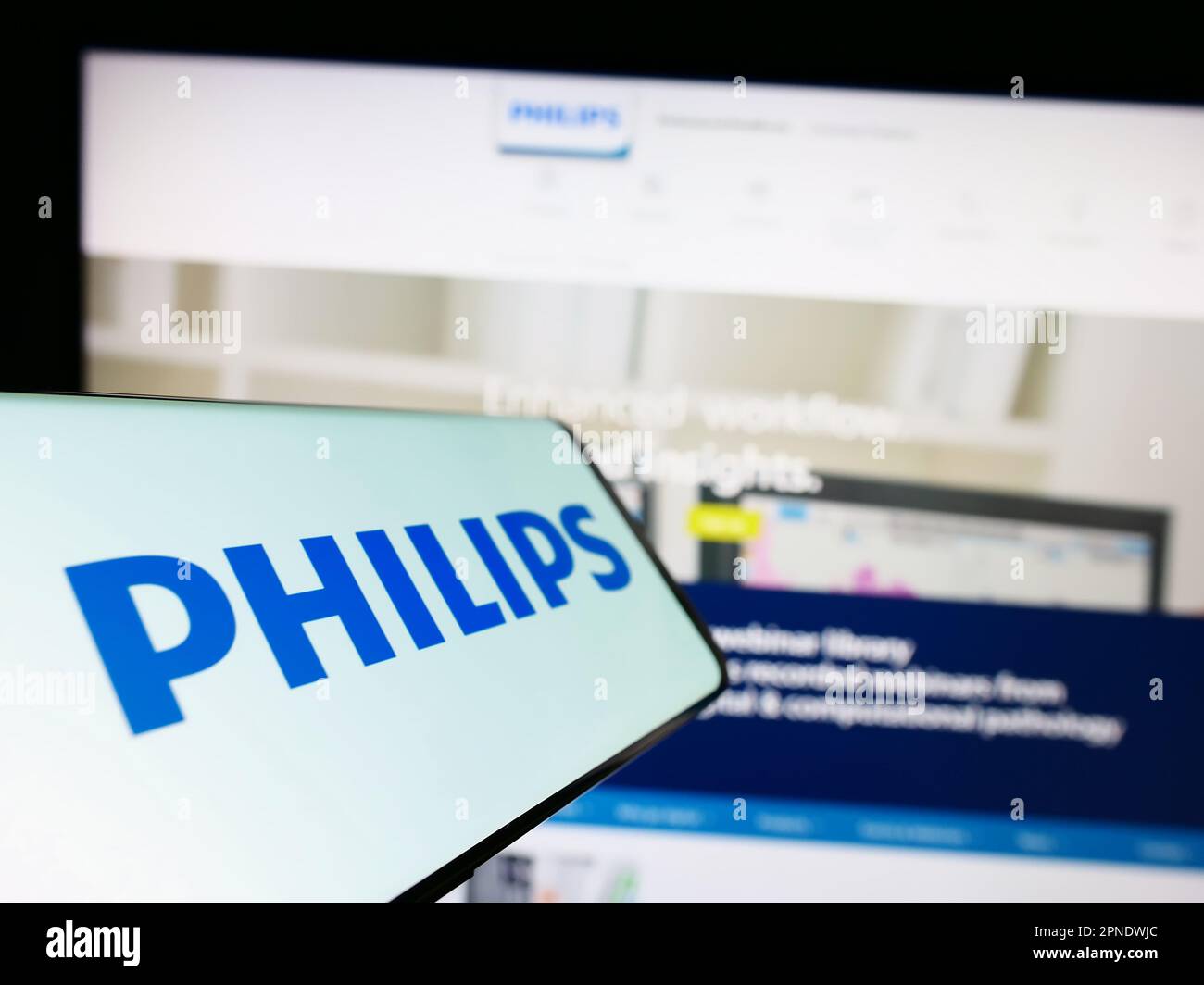 Smartphone with logo of Dutch company Koninklijke Philips N.V. on screen in front of business website. Focus on center-left of phone display. Stock Photo