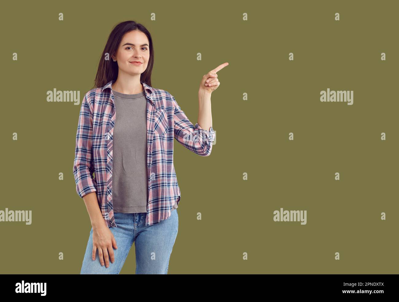 Young woman wearing casual clothes pointing at copy space side on khaki background Stock Photo