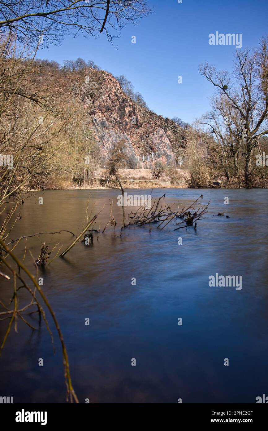 Plants in water in the Nahe River with Rotenfels in the background on a sunny winter day in Bad Kreuznach, Germany. Stock Photo