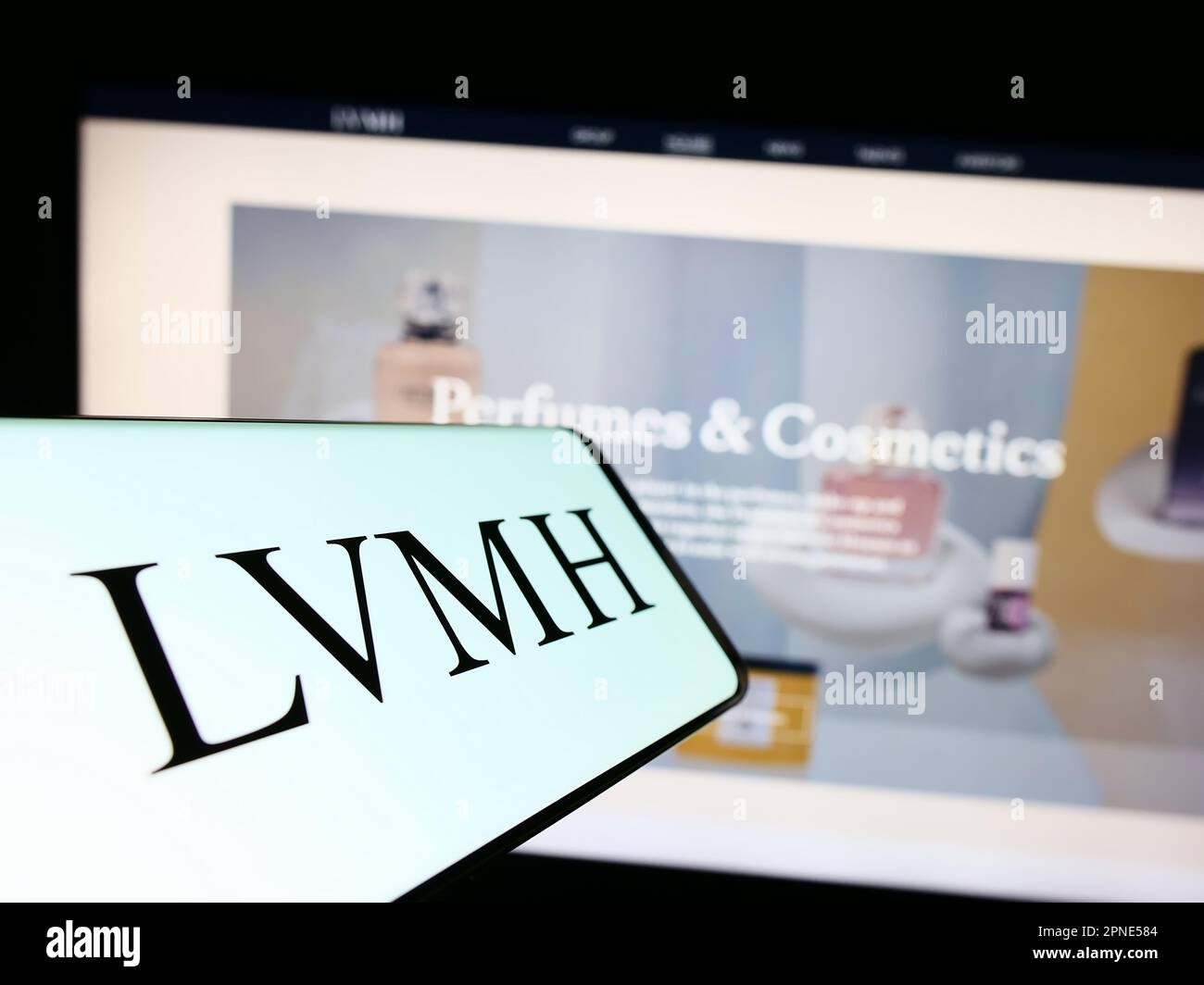 Mobile phone with logo of company LVMH Moet Hennessy Louis Vuitton SE on screen in front of business website. Focus on center of phone display. Stock Photo