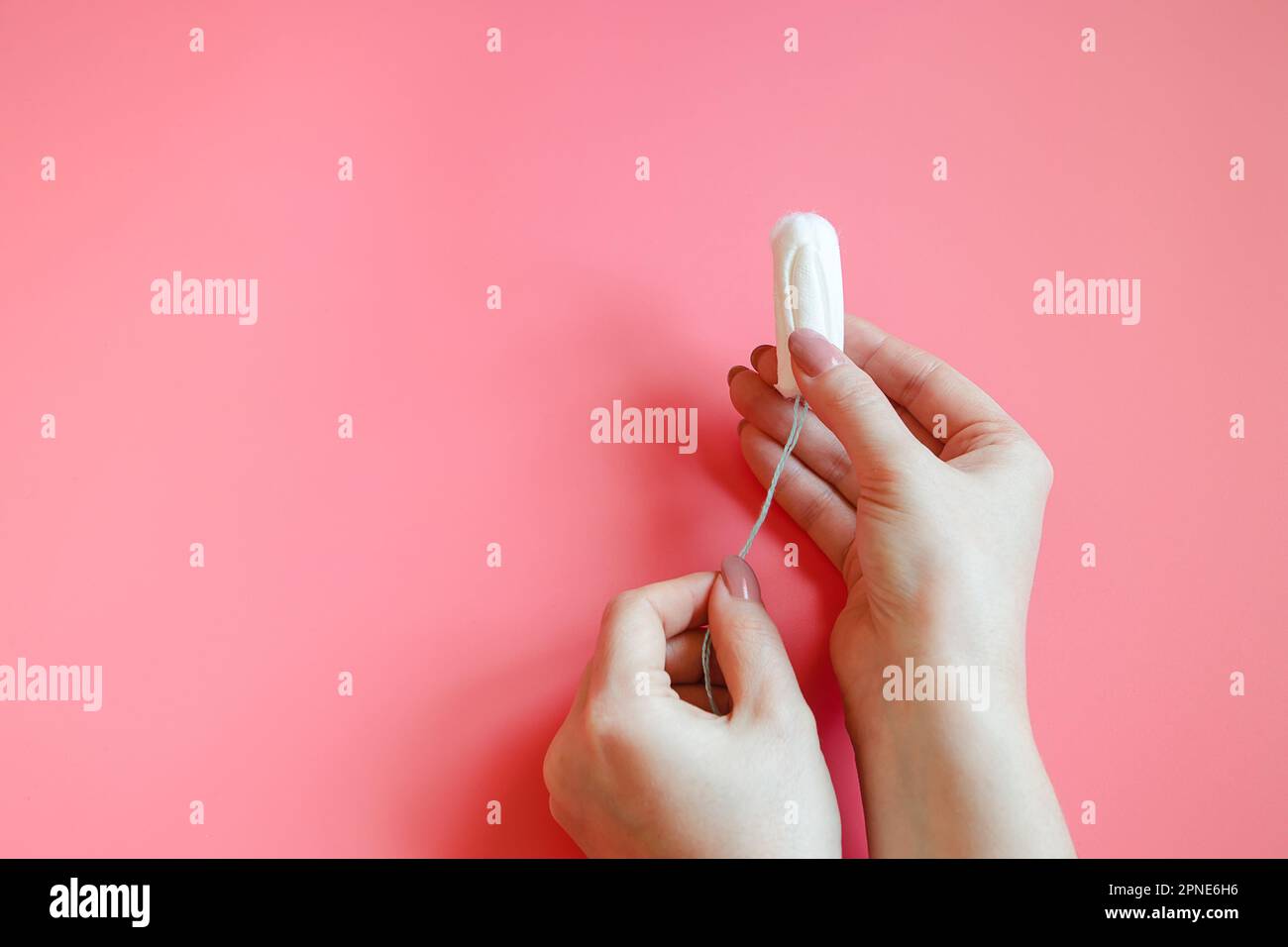 Woman is holding hygienic cotton tampon in her hands. Proper use of tampons. Concept of intimate