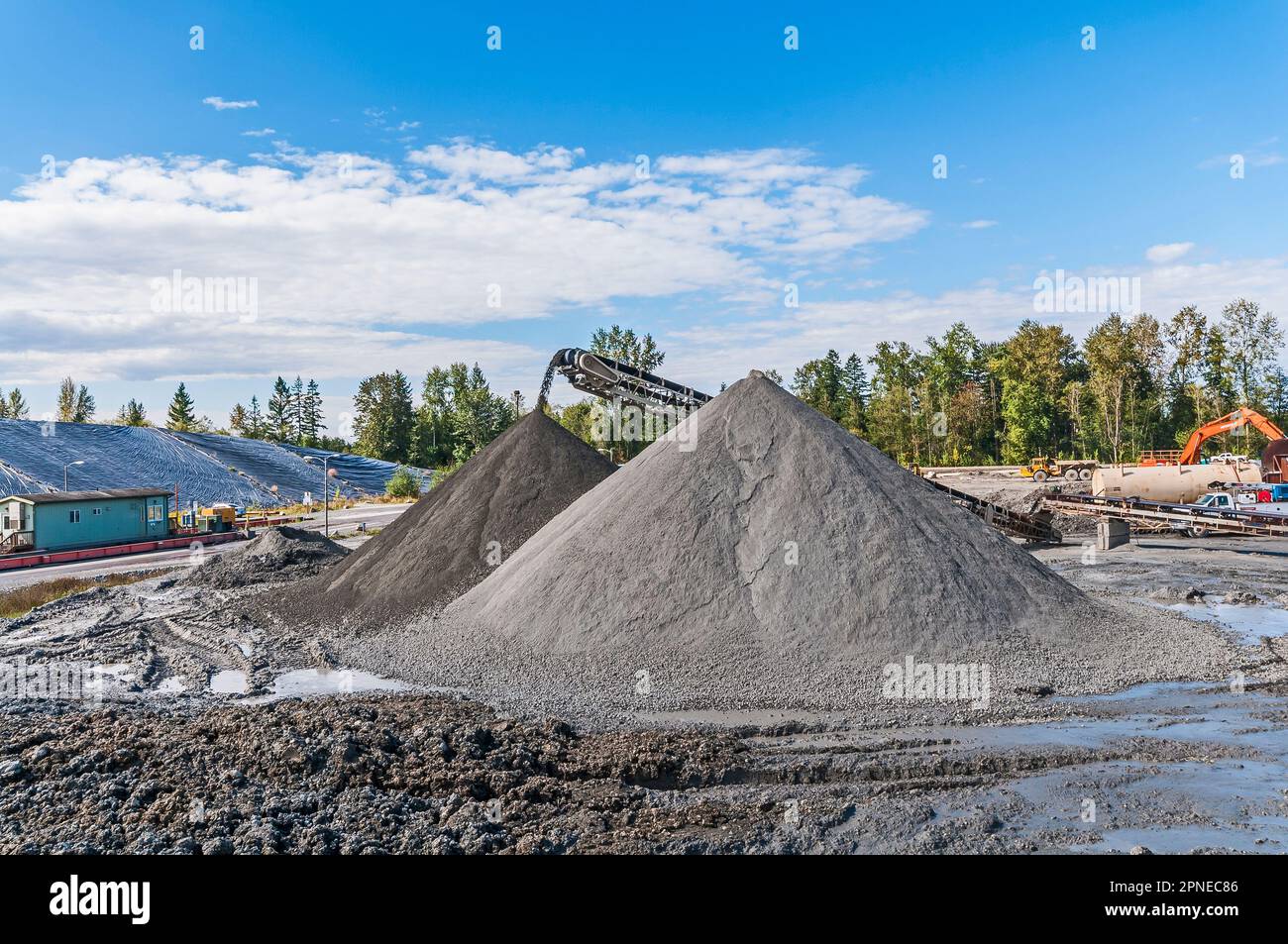 Small peaked, cone-shaped hills of dirt dumped by a conveyor belt in an active landfill. Stock Photo