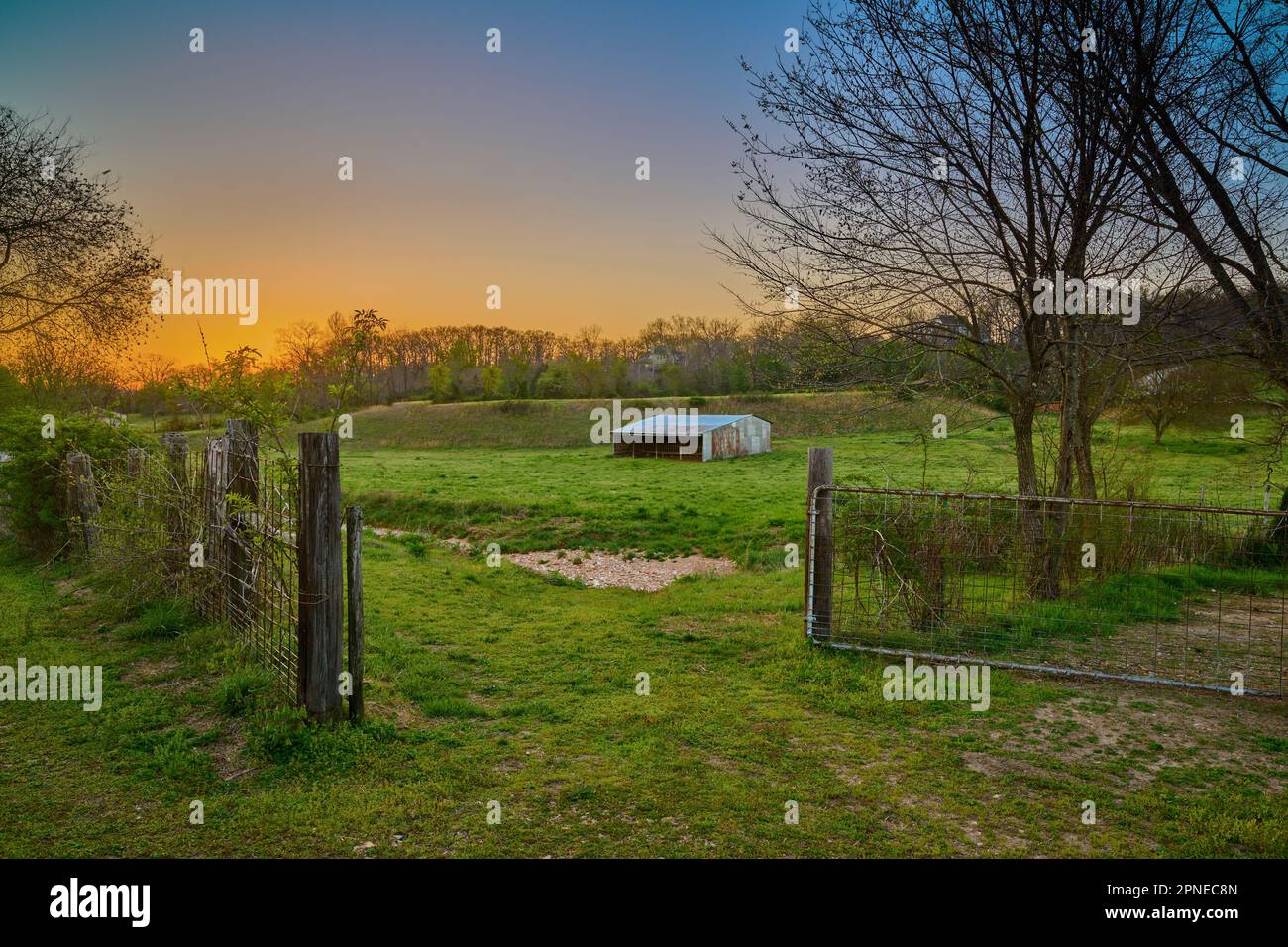 Sunset over a farm with old barn and gate near Bentonville Arkansas. Stock Photo