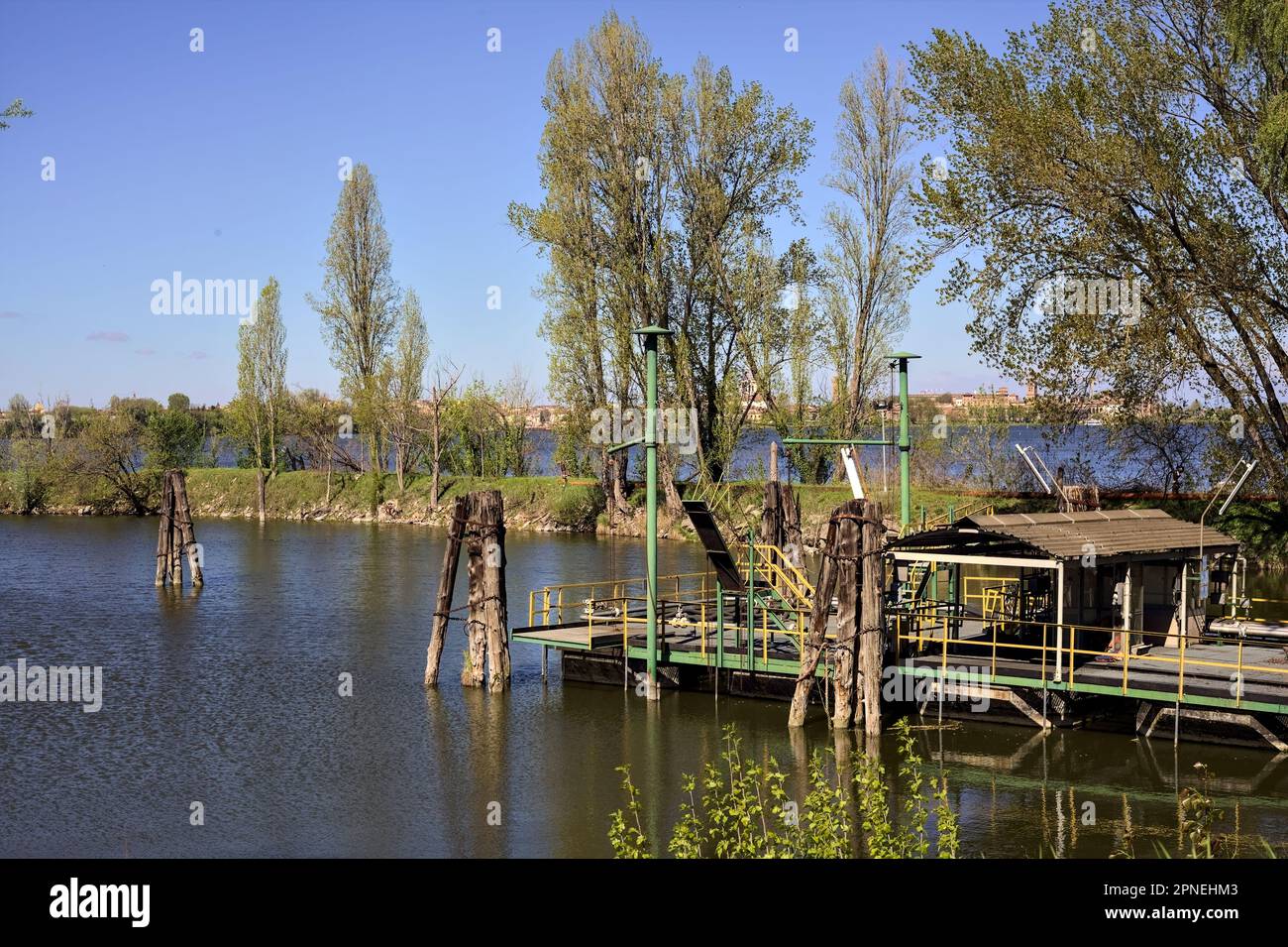 Inlet with wooden poles and a barge by the shore in a forest next to an ...