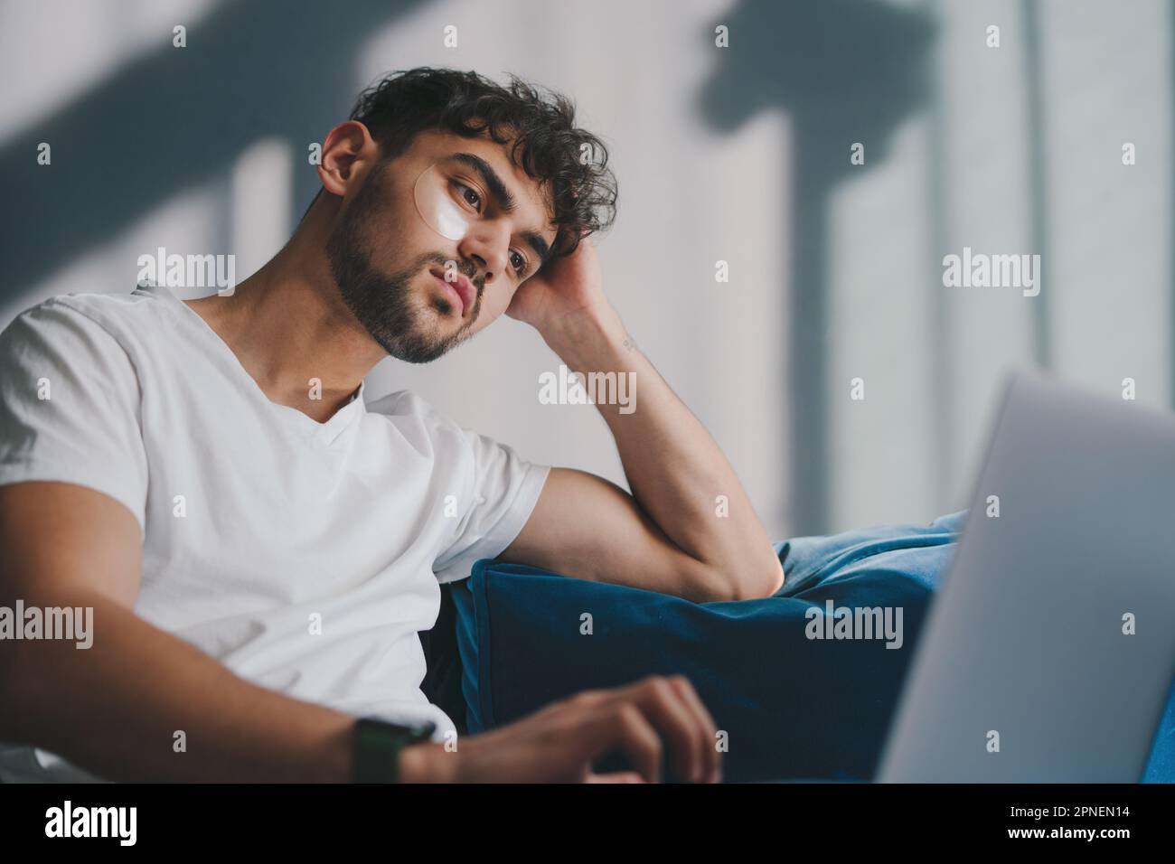 Handsome cheerful young man indoors at home on sofa using laptop computer. Education internet technology. Home comfort. Stock Photo