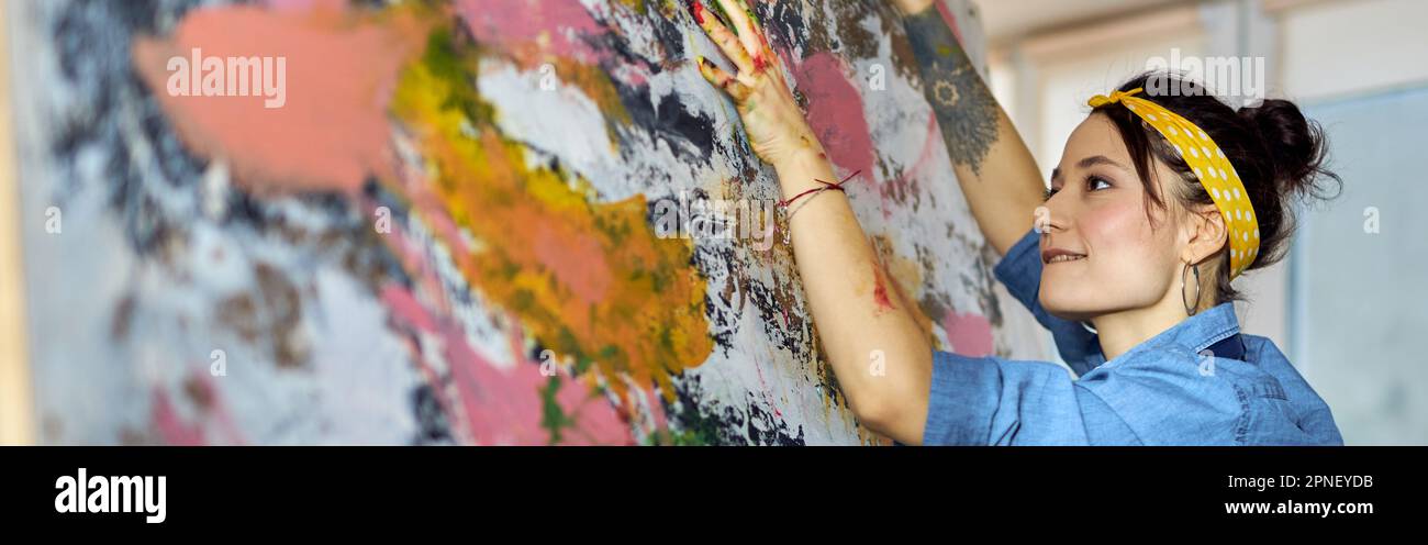 Paint Working Concentrated young female painter working on a large modern abstract ...