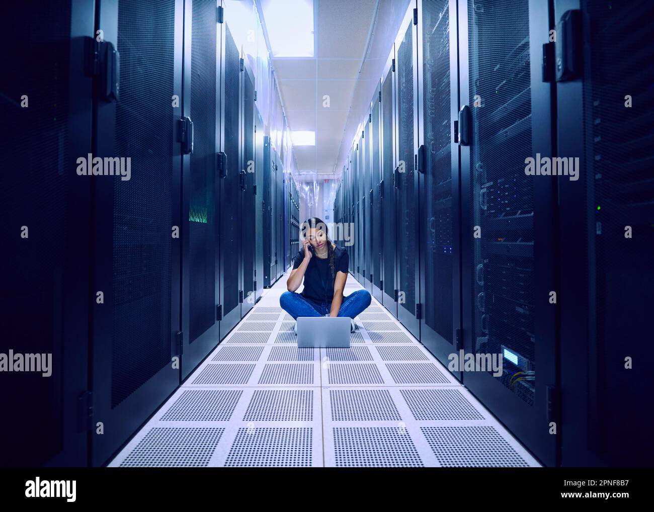 Female technician using laptop and phone in server room Stock Photo Alamy