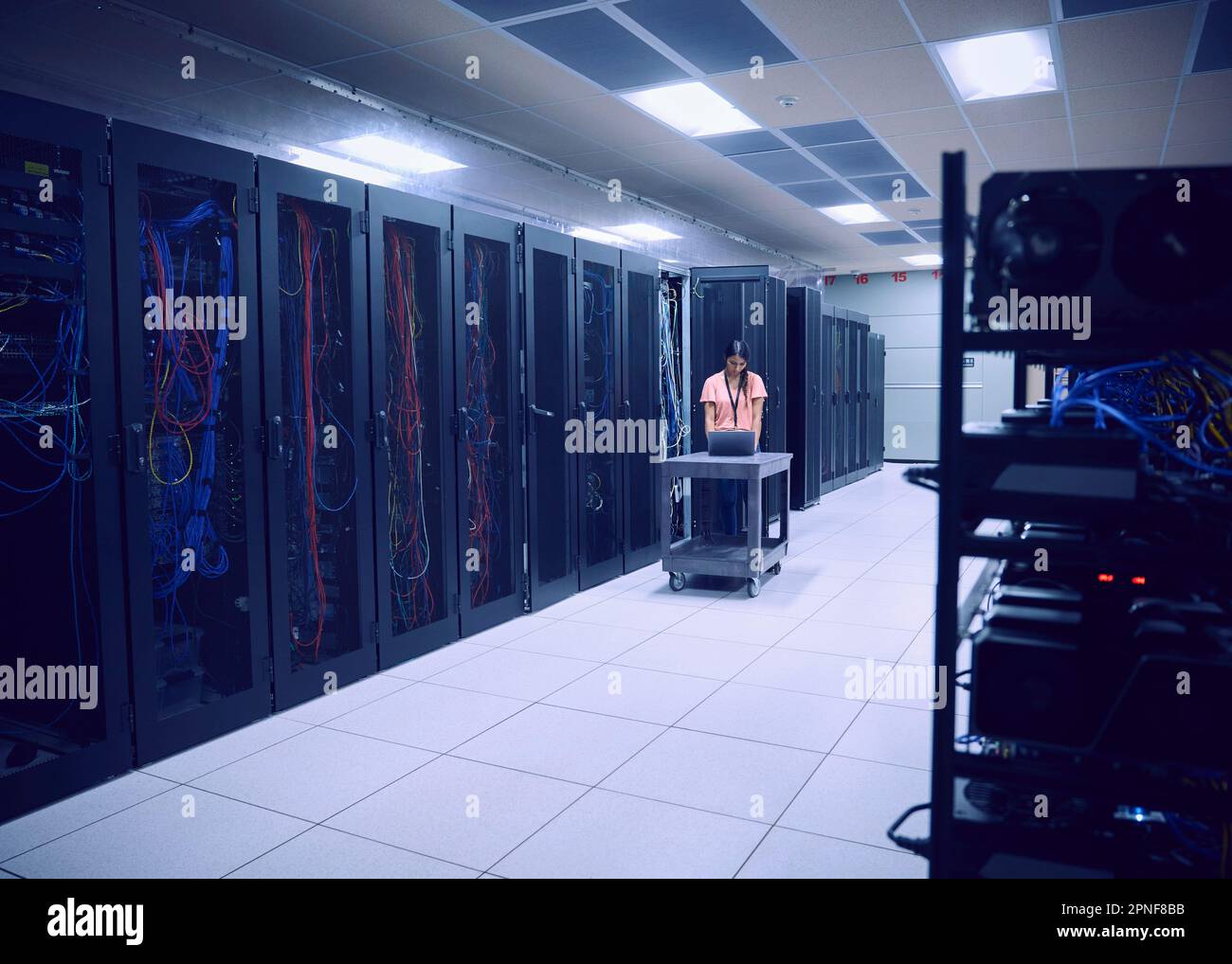 Female technician using laptop in server room Stock Photo