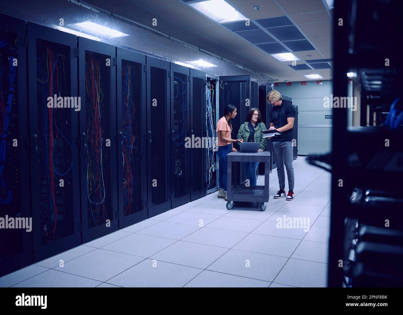 Team of technicians working in server room Stock Photo