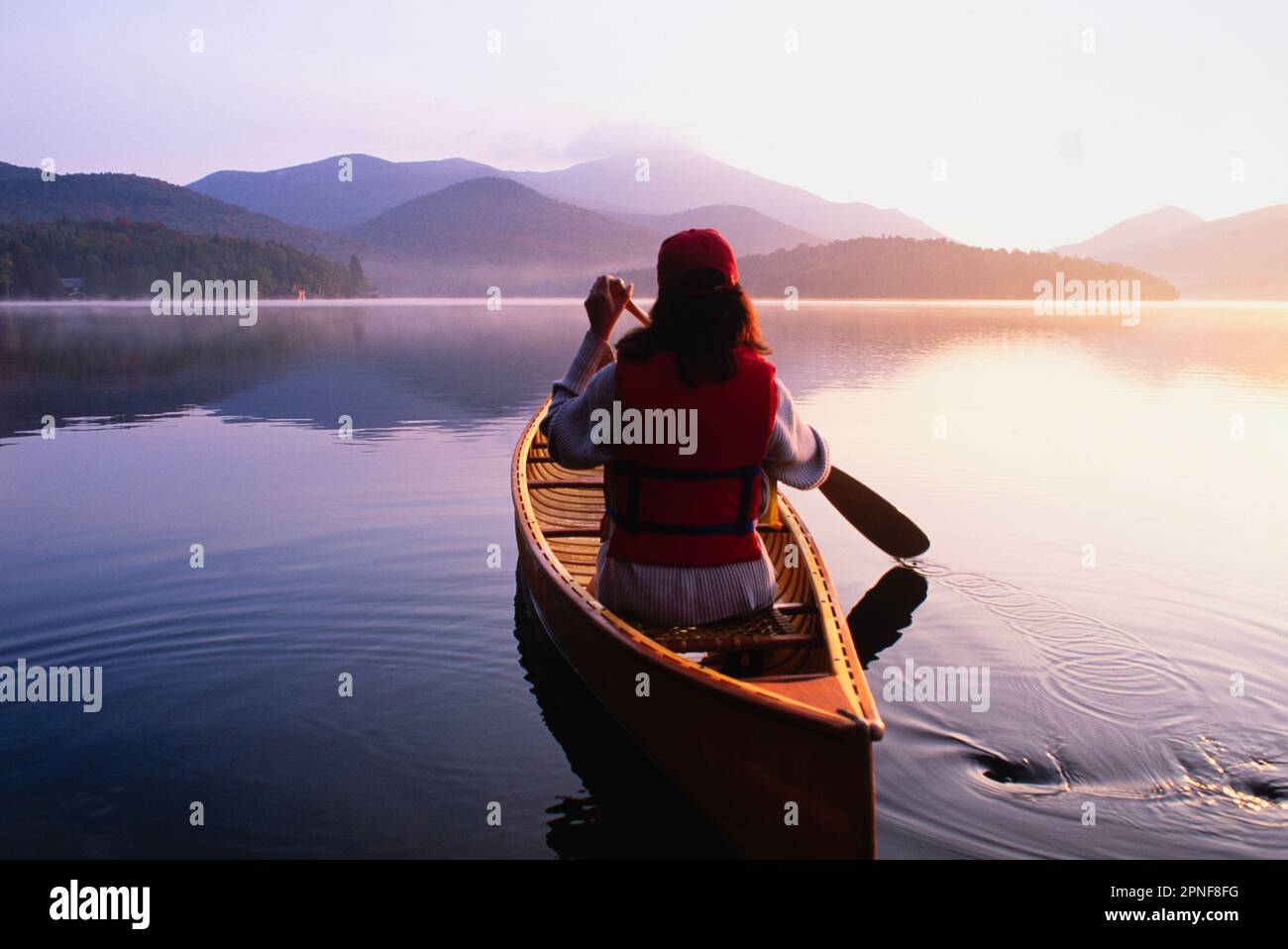 United States, New York, Rear view of woman paddling canoe on Lake ...