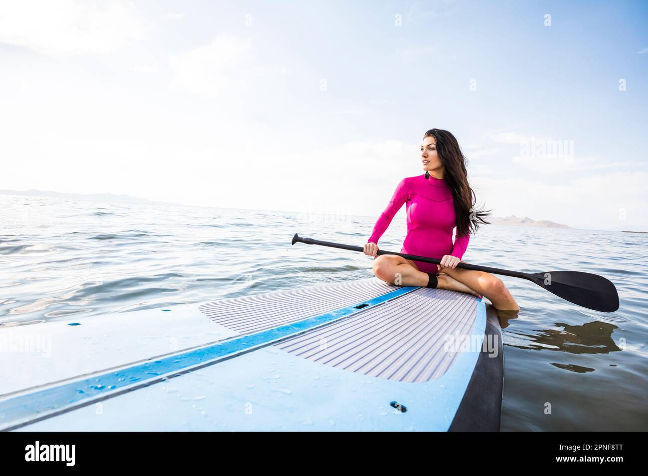 Woman sitting on paddleboard Stock Photo