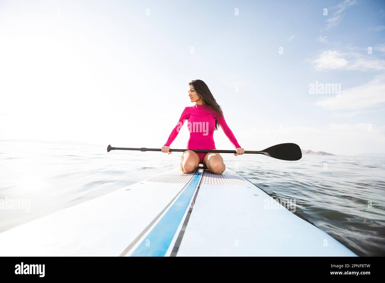 Woman kneeling on paddleboard Stock Photo