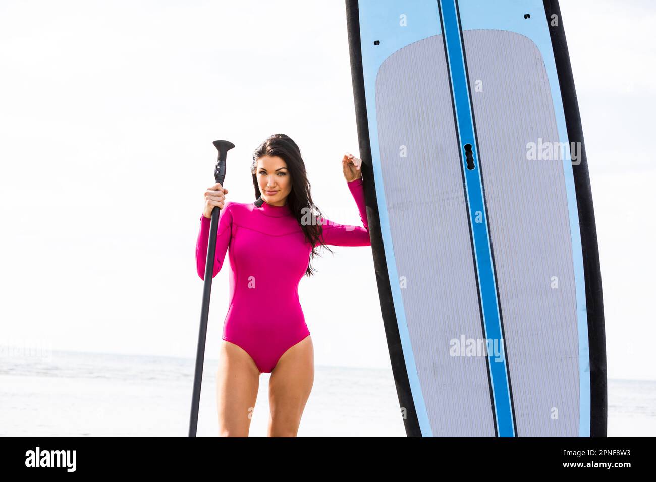 Woman standing next to paddleboard and holding oar Stock Photo