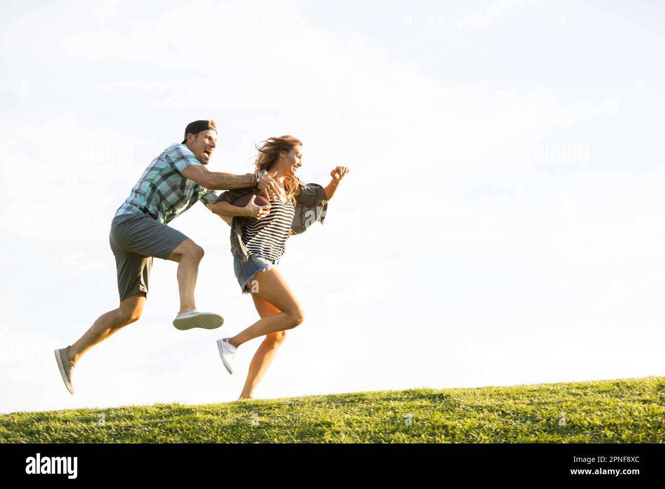 Woman and man running on hill in park Stock Photo