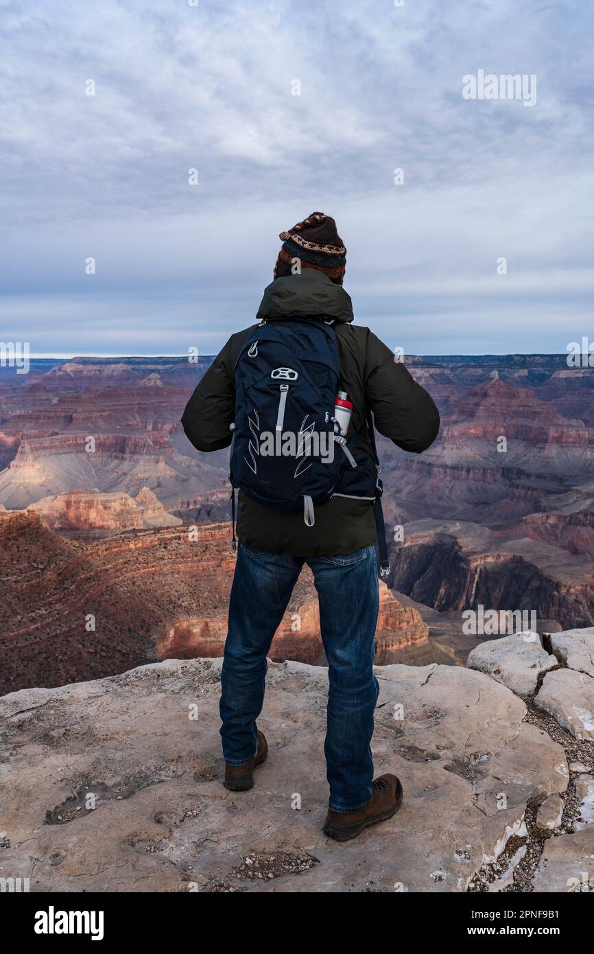 United States, Arizona, Grand Canyon National Park, South Rim, Senior male hiker standing at edge of Grand Canyon at sunrise Stock Photo