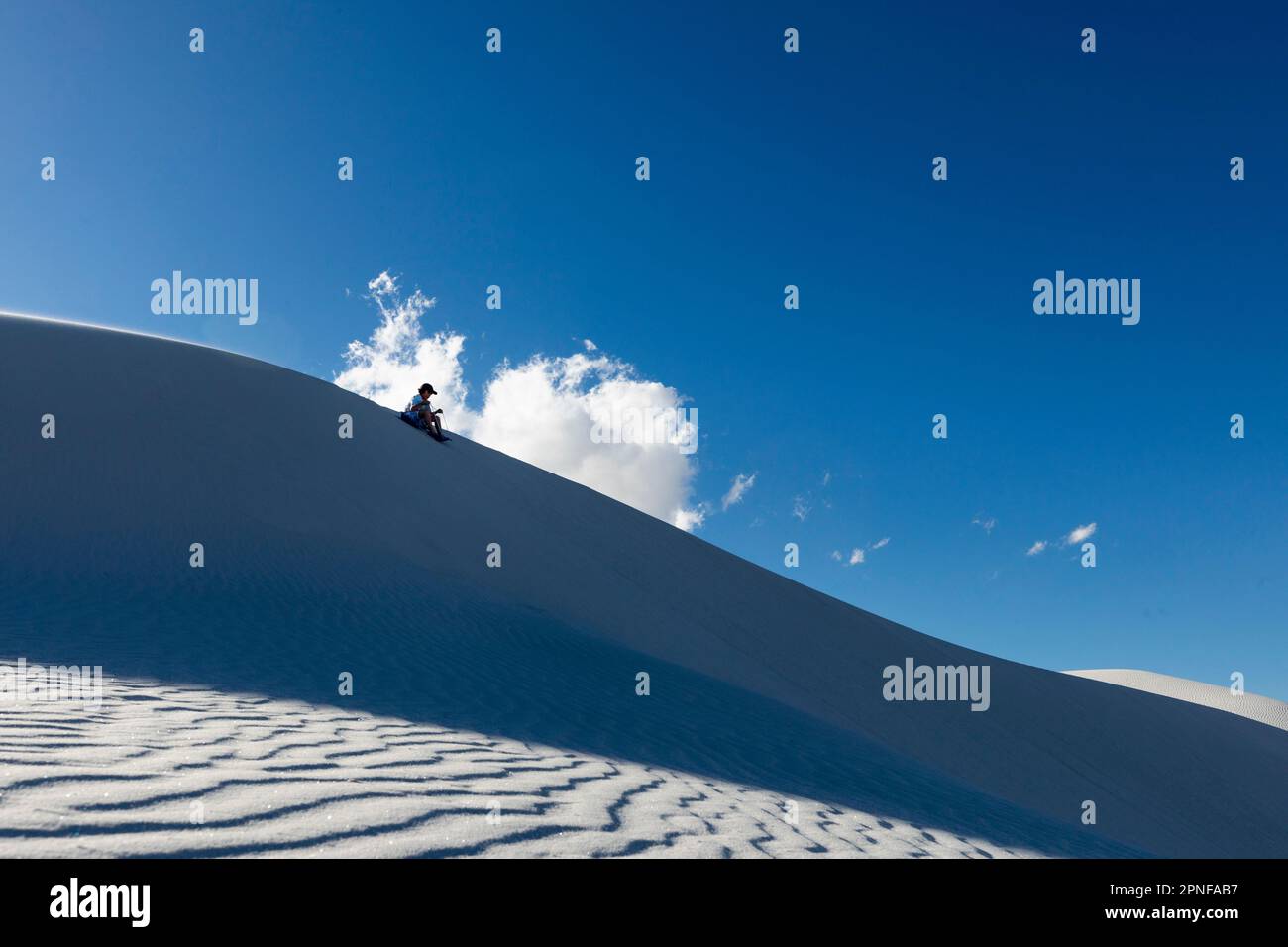 United States, New Mexico, White Sands National Park, Boy (10-11) sand boarding in desert Stock Photo