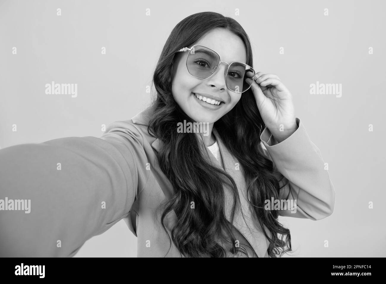 Trendy beautiful teenage model making selfie posing on yellow studio ...