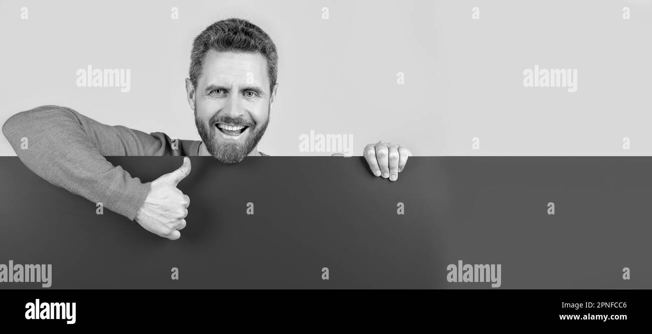 Man face portrait, banner with copy space. product presenting. presenting novelty information. male behind blue paper show thumb up. Stock Photo