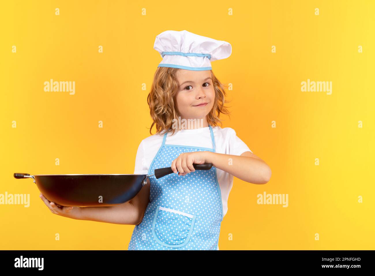 Little cook with cooking pan. Cooking, culinary and kids. Little boy in chefs hat and apron on studio isolated background Stock Photo