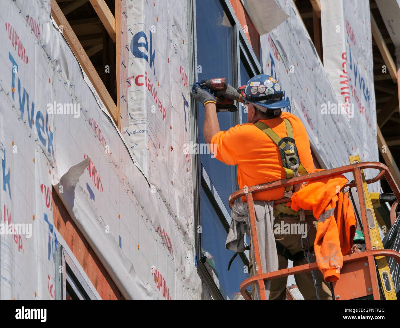 Construction workers installing window in highrise apartment building under construction. Stock Photo