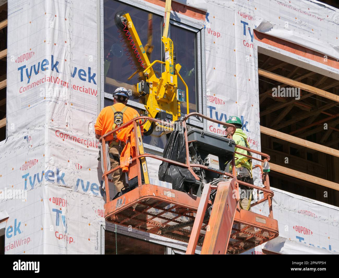 Construction workers installing window in highrise apartment building under construction. Stock Photo