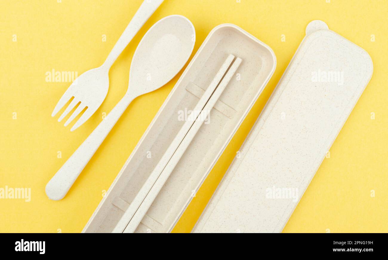 Plastic spoons, forks and chopsticks set on yellow background Stock