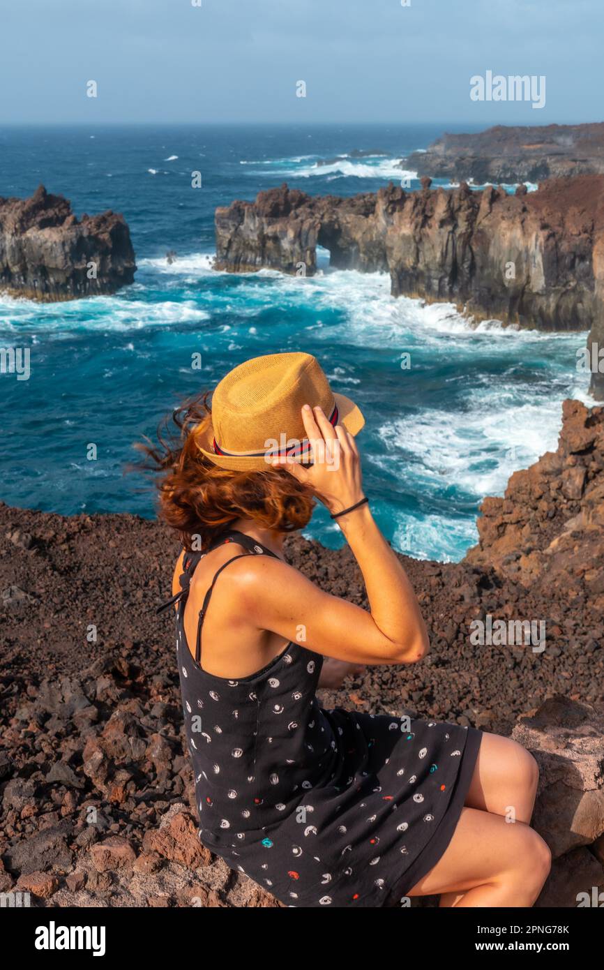 El Hierro Island. Canary Islands, a young tourist in the Arco de la Tosca sitting. monument on the coast Stock Photo