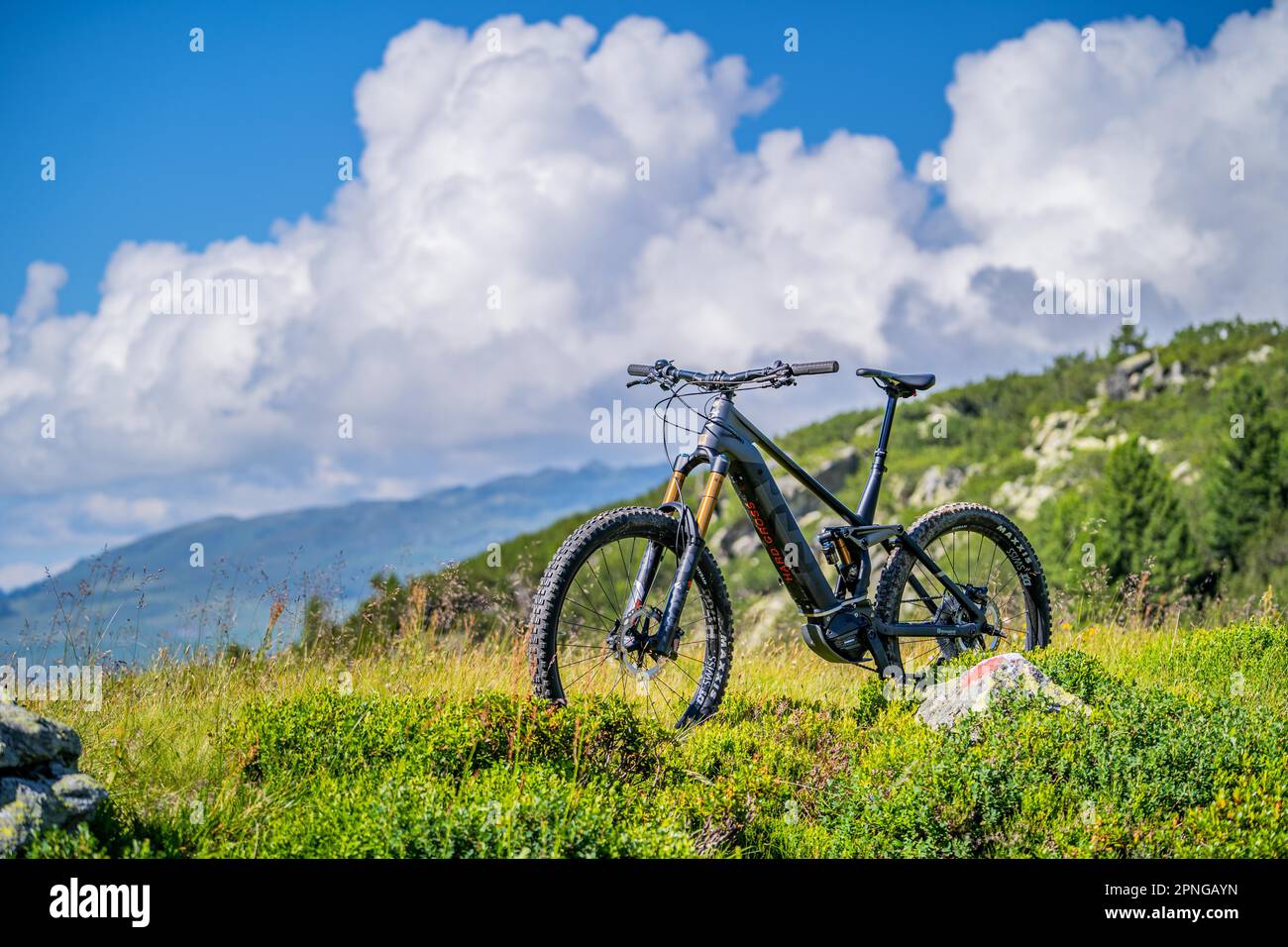 On a sunny summer day on the road with the e-bike in the Zillertal Alps, away from asphalted roads and hiking trails, in the background the Stock Photo