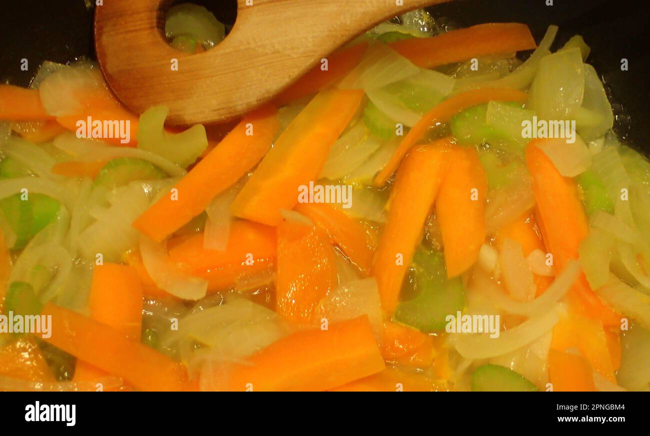 Carrot slices and onion slices and chopped celery simmering Stock Photo