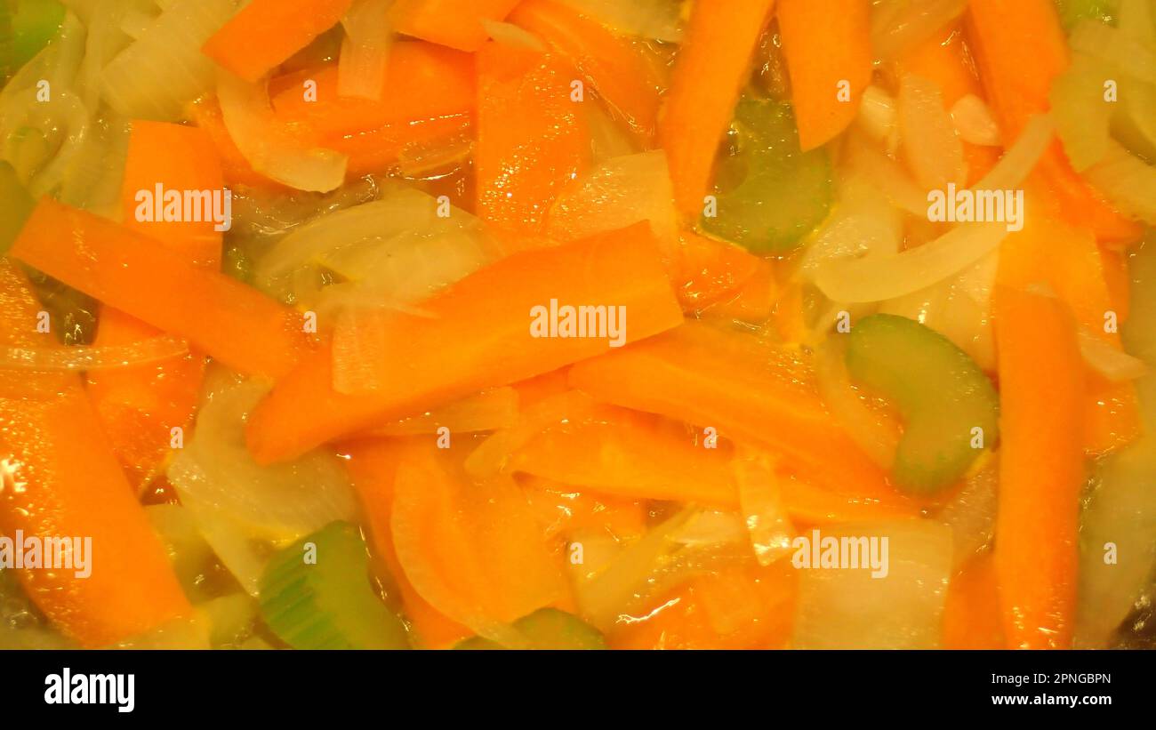 Carrot slices and onion slices and chopped celery simmering Stock Photo