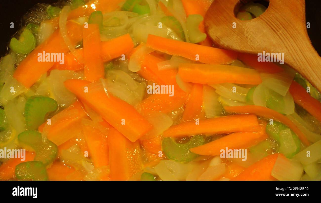 Carrot slices and onion slices and chopped celery simmering Stock Photo