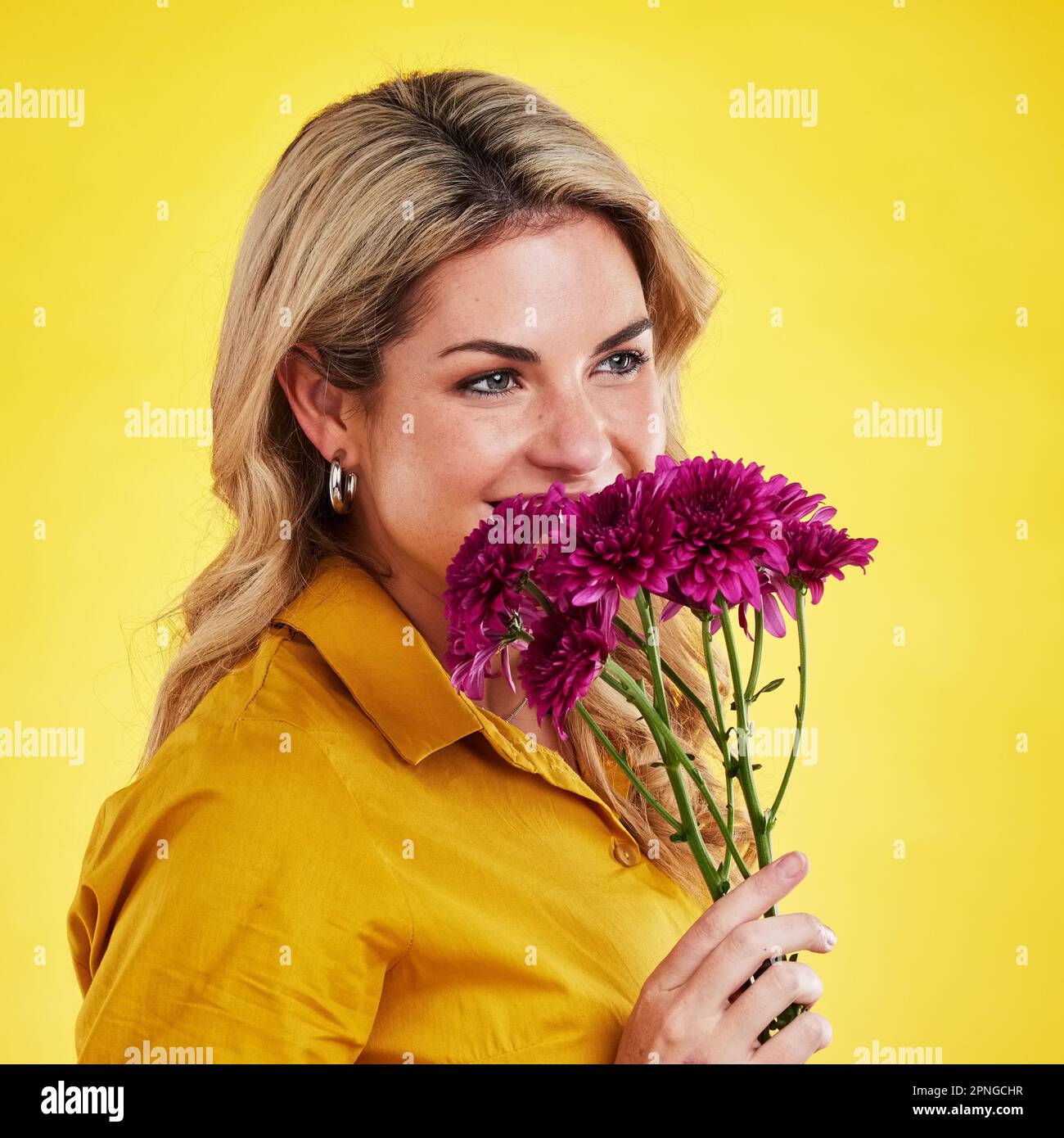 Portrait, smile and woman smelling flowers in studio isolated on a yellow background. Floral