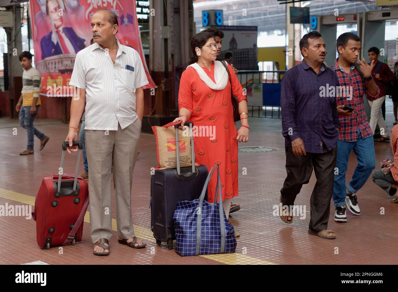 A middle-aged Indian couple with suitcases waiting for their train; Chhatrapati Shivaji Maharaj Terminus, the busiest railway station in Mumbai, India Stock Photo