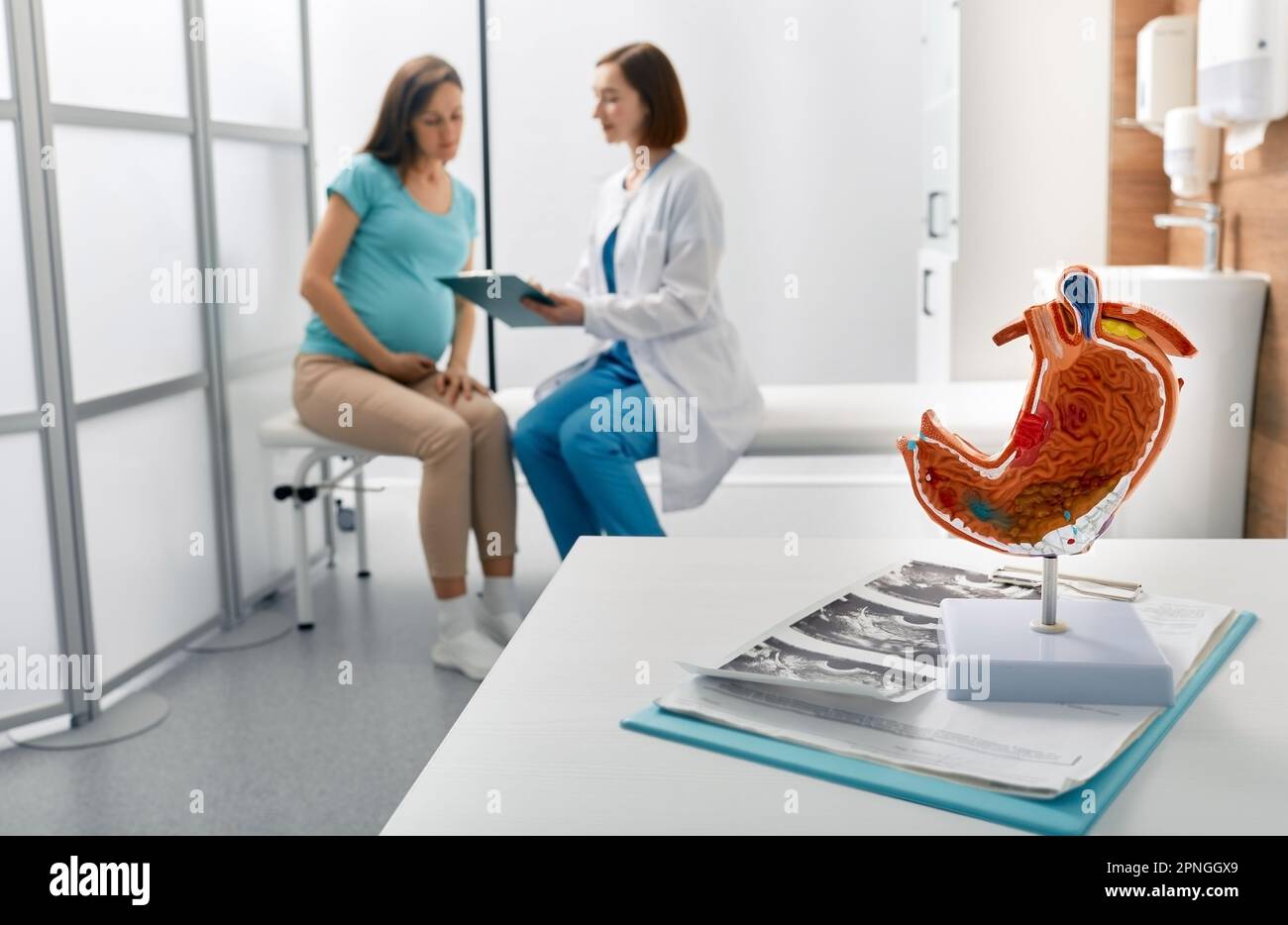 Pregnant woman with heaviness in stomach at appointment with gastroenterologist. Stomach problems, heartburn in pregnancy Stock Photo