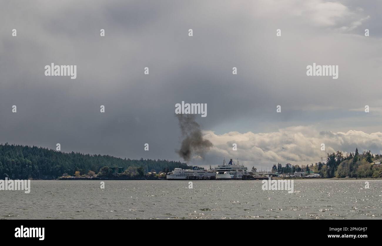 A puff of black smoke drifts aways from the exhaust pipe of a large BC Ferries ship while it is docked in Departure Bay, Nanaimo, BC, Canada. Stock Photo