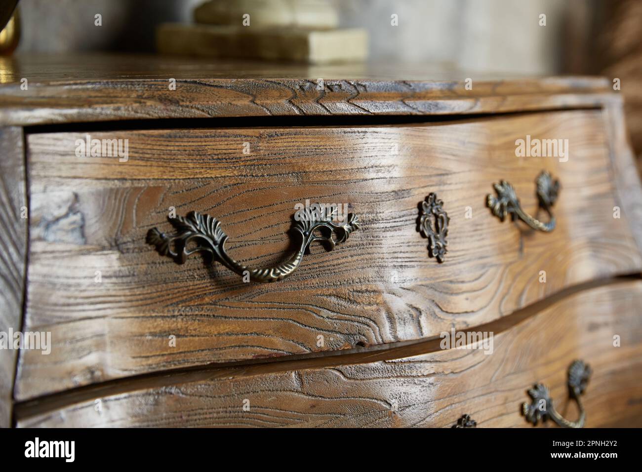 Vintage curved chest of drawers close-up. Forged handles. Stock Photo