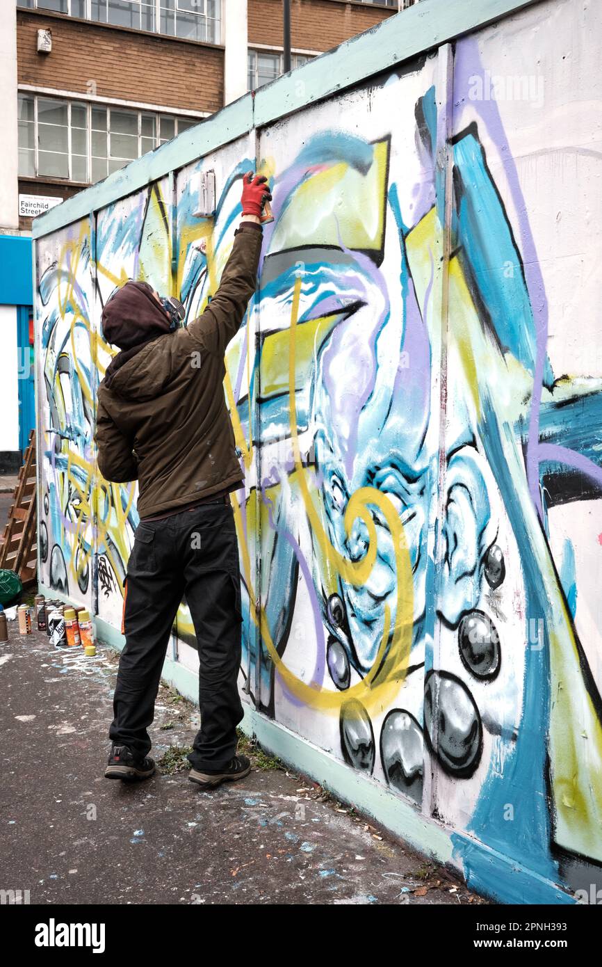 Graffiti artist, wearing a breathing mask, using a spray can on