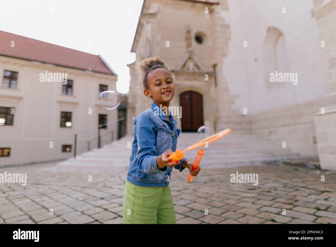 Multiracial girl playing outdoor with bubble blower Stock Photo - Alamy