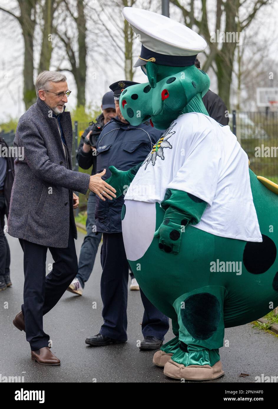 Chemnitz, Germany. 19th Apr, 2023. The police mascot Poldi greets Armin Schuster (CDU), Interior Minister of Saxony, in front of Rabenstein Elementary School in Chemnitz. Supported by students from a third grade class, the police carry out their traffic safety campaign 'Blitz für Kids' in front of the elementary school. Throughout the Free State, the police conduct speed checks in front of selected elementary schools together with ADAC Saxony. Credit: Hendrik Schmidt/dpa/Alamy Live News Stock Photo