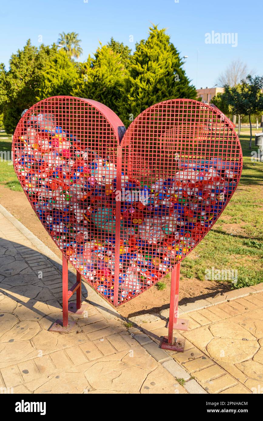 A heart-shaped container for recycling plastic bottle caps, symbolising our love for the planet. Recycling plastics helps to reduce pollution and keep Stock Photo