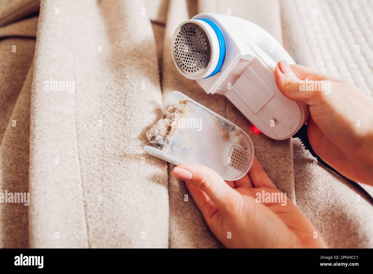 Cleaning lint remover after shaving fuzz on garment. Taking off container full of trimmed pilling and dirt. Taking care of device Stock Photo