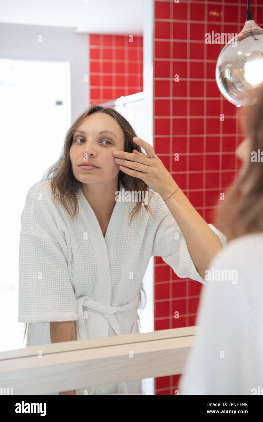 Skincare routine white female in a bright bathroom shaving legs with a