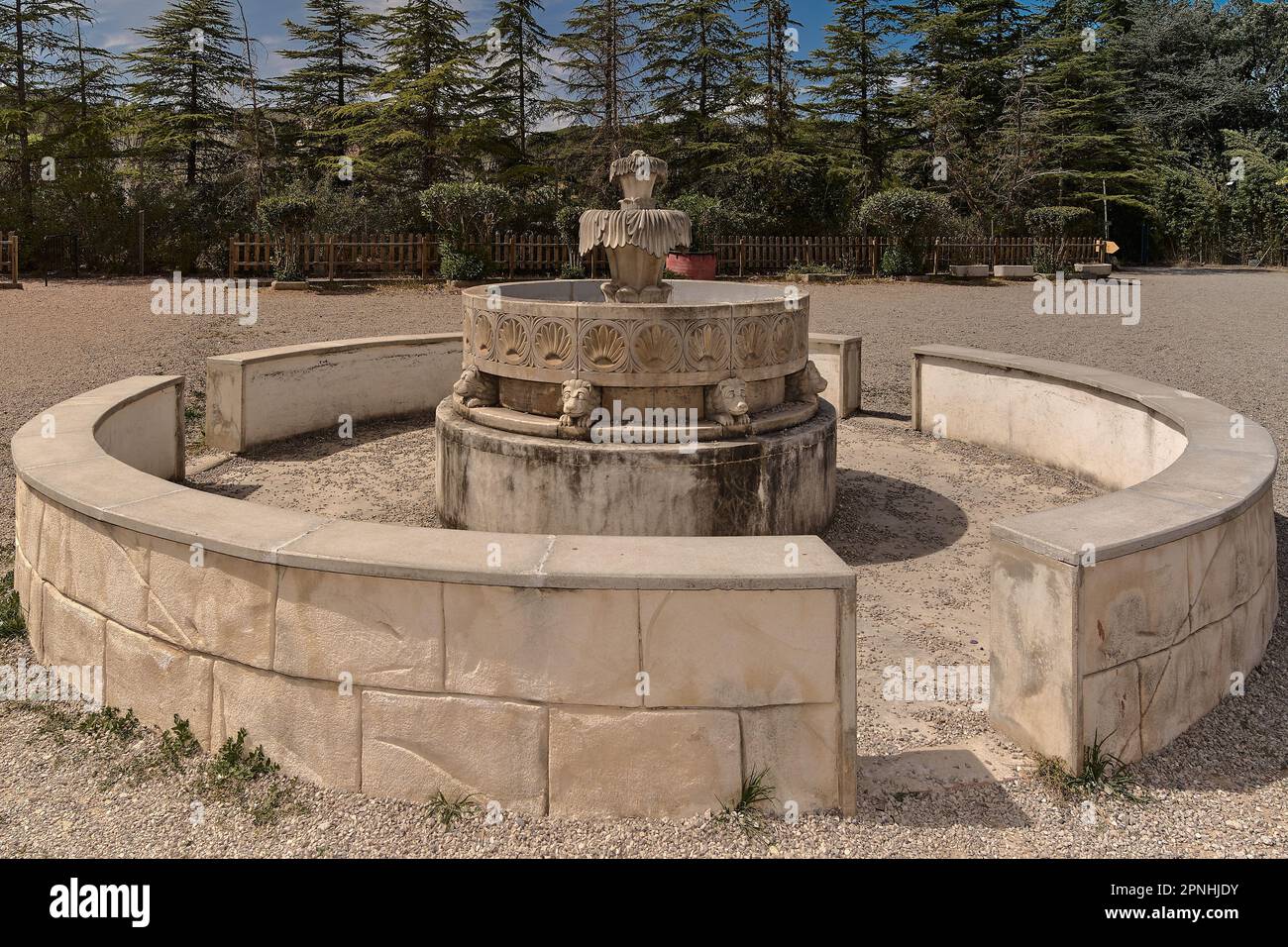 Completely dry fountain, with green trees in the background, in the concept of water scarcity and drought. Stock Photo