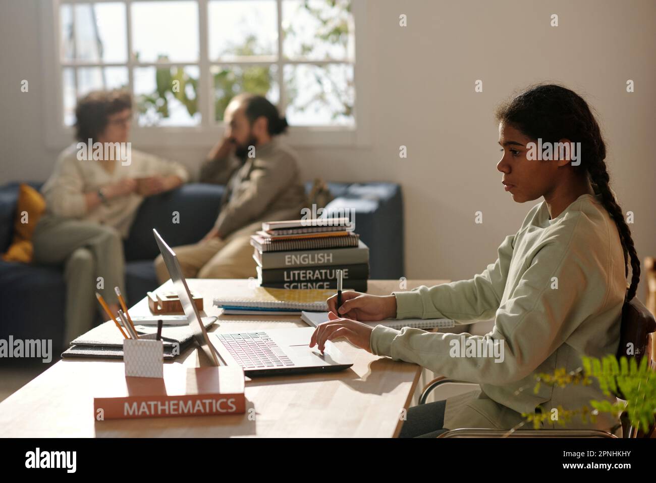 African American girl using laptop to do her homework at desk in the