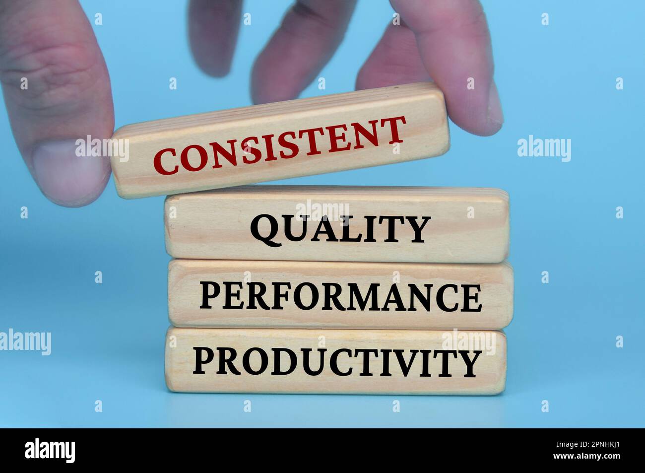 Hand lifting wooden block with text consistent quality performance ...