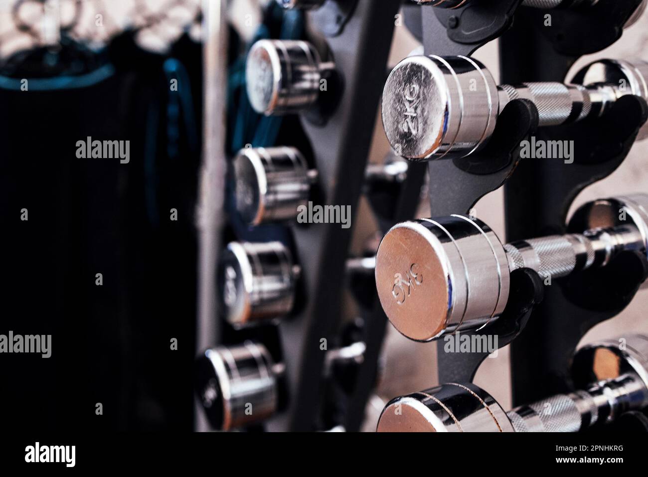 Close up of rack with modern metal dumbbells. Sports equipment in the ...