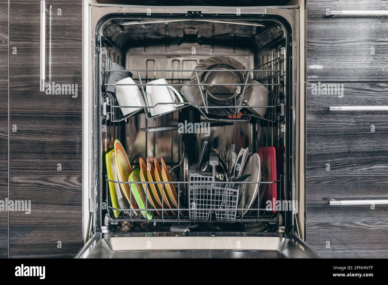 Open dishwasher with dishes built into the kitchen Stock Photo