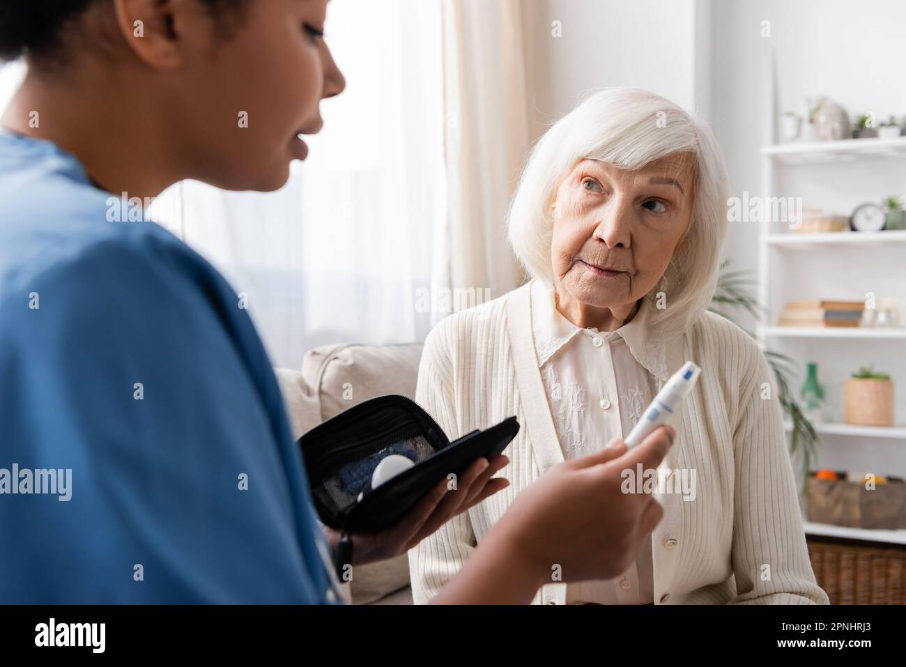 multiracial nurse holding lancet pen and explaining how to use it to