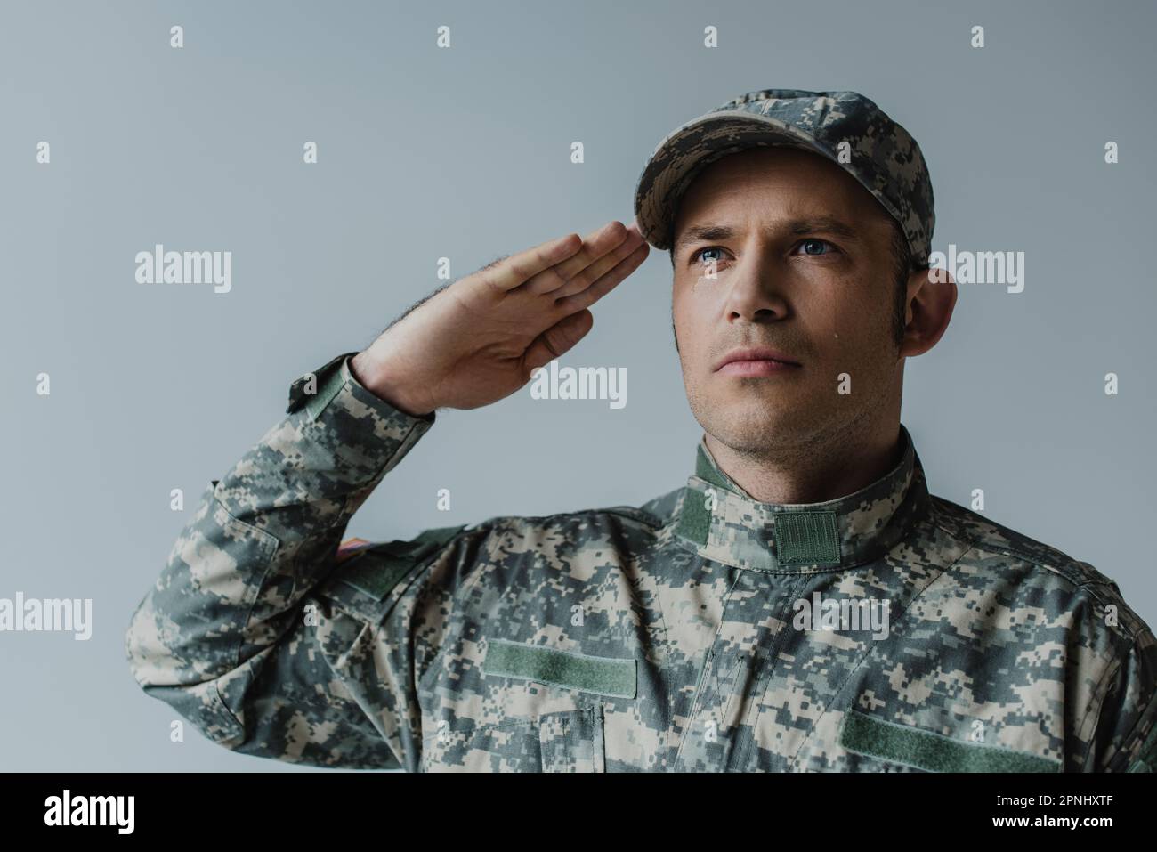 upset soldier in military uniform saluting and crying during memorial day isolated on grey Stock Photo